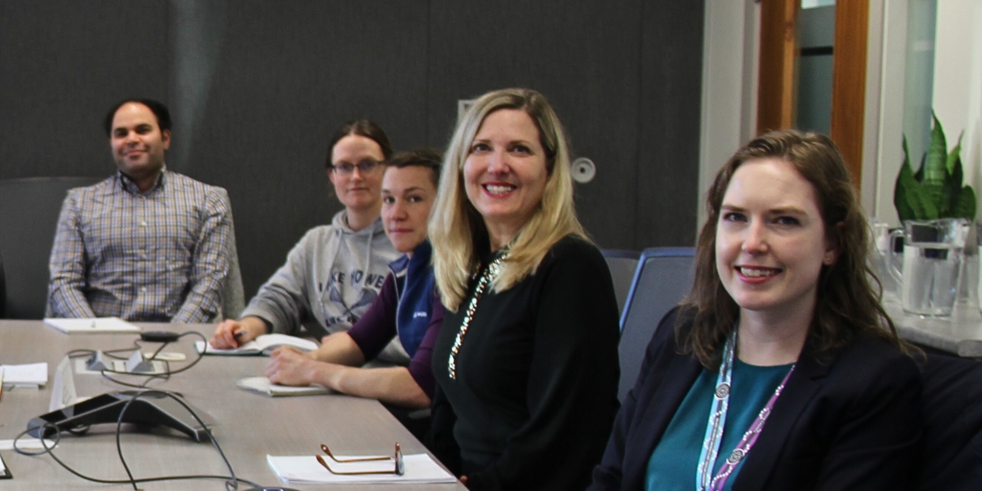 Jean Smart from Clinical Trials BC sitting at a table, surrounded by learners. They are all smiling with notebooks in front of them.