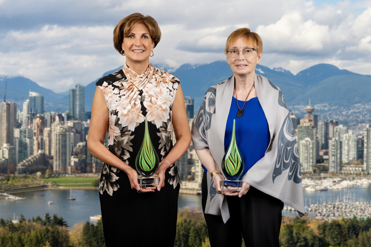 Two recipients of the Clinical Trials British Columbia Awards 2026, smiling and standing against a city skyline while holding glass awards.